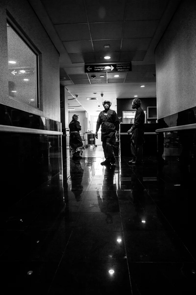 Pasillo largo y oscuro del área COVID con personal al fondo