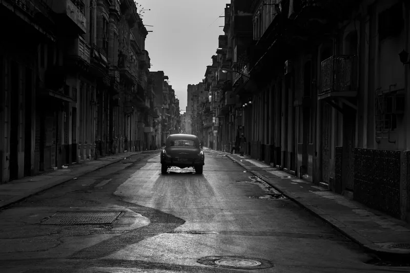 Un auto clásico avanza por una calle vacía