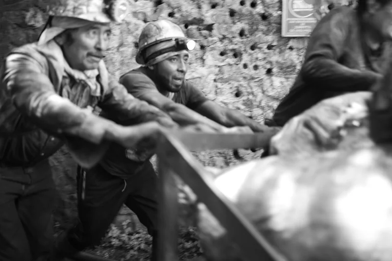 Mineros empujan un carro cargado de piedra