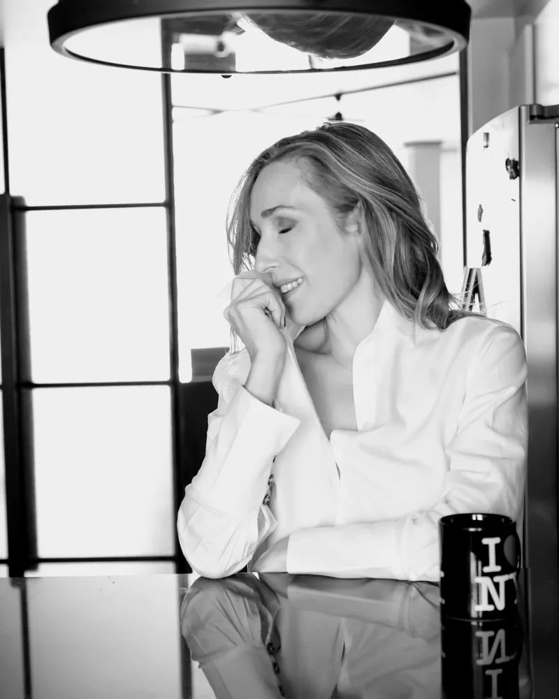 Retrato en blanco y negro de una mujer con camisa blanca, riendo